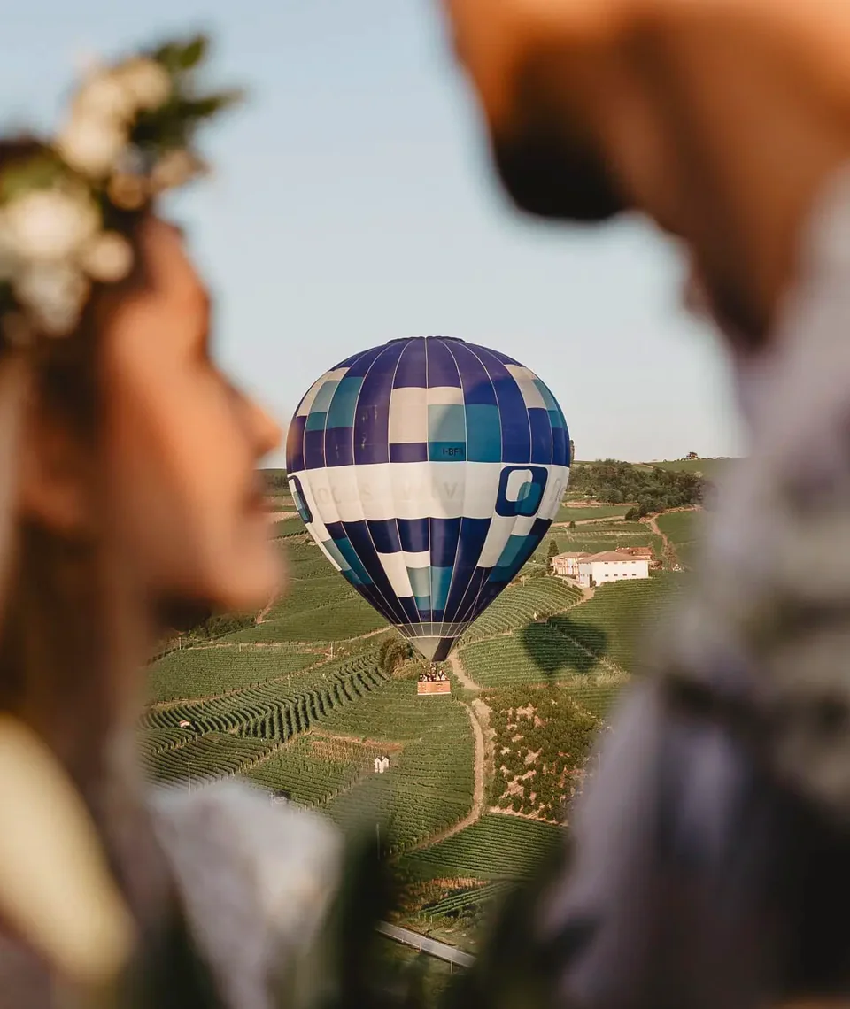 A couple looking towards a hot air balloon above vineyard hills