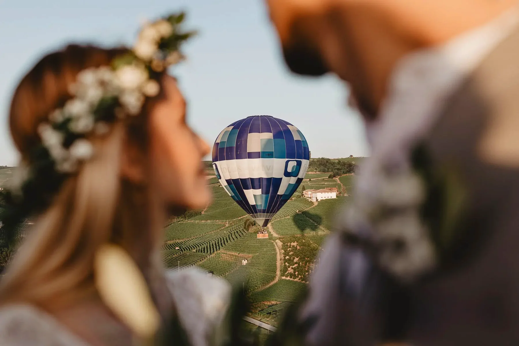 Casal em primeiro plano e um balão sobre os vinhedos